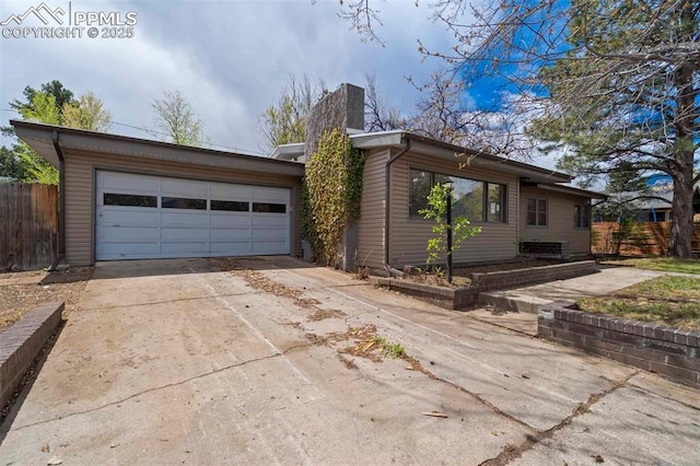 view of side of property featuring a garage, fence, driveway, and a chimney
