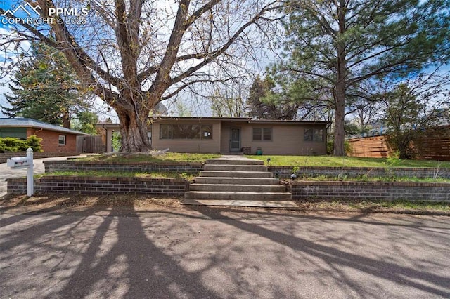 ranch-style house featuring fence and a front lawn