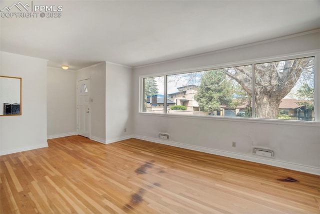 unfurnished room featuring baseboards, ornamental molding, and light wood finished floors