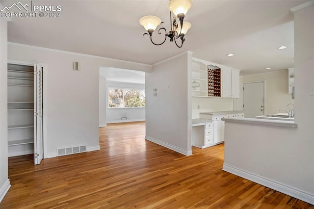 unfurnished dining area with ornamental molding, light wood finished floors, and visible vents