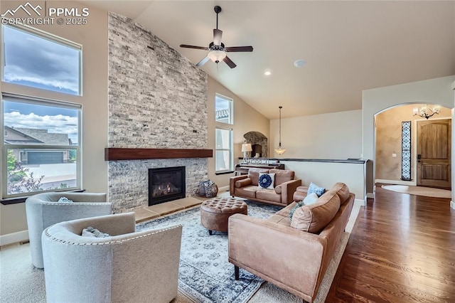 living room featuring baseboards, a healthy amount of sunlight, ceiling fan with notable chandelier, and high vaulted ceiling