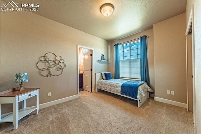 bedroom with carpet floors, a textured ceiling, baseboards, and ensuite bathroom