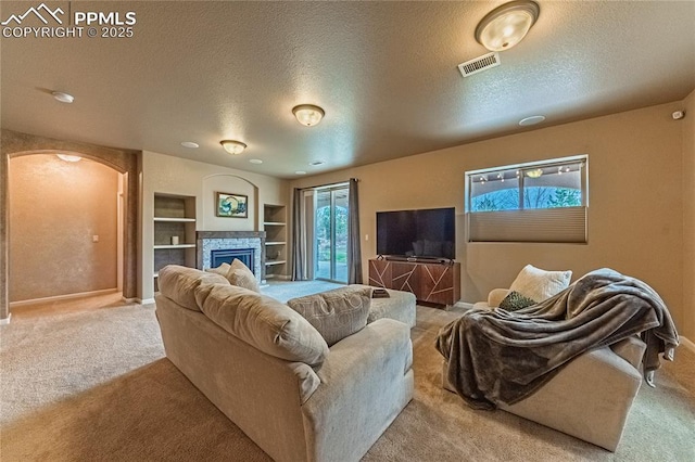 carpeted living room featuring built in shelves, baseboards, a textured ceiling, and visible vents
