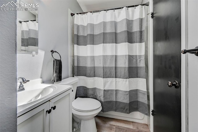 full bathroom with vanity, toilet, a textured wall, and wood finished floors