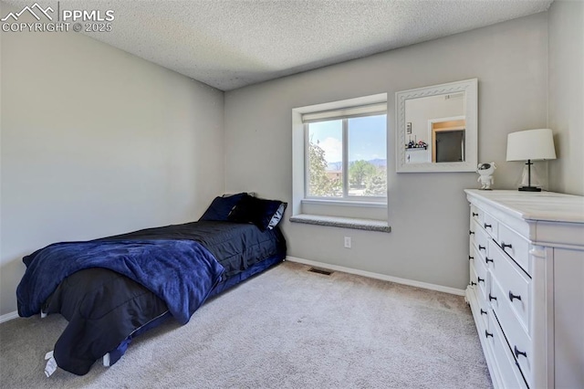 bedroom featuring a textured ceiling, baseboards, visible vents, and light colored carpet