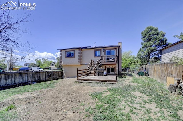 back of house featuring solar panels, a wooden deck, a fenced backyard, and stairs