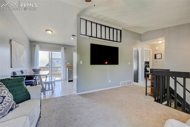 carpeted living room featuring a textured ceiling, baseboards, and visible vents