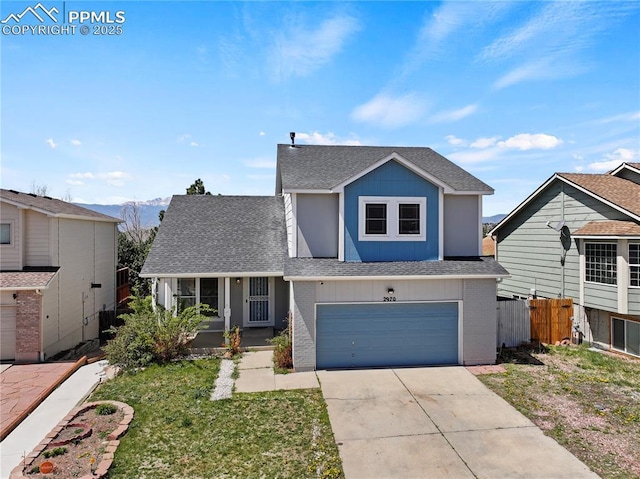 traditional-style home featuring fence, a front yard, a shingled roof, an attached garage, and driveway