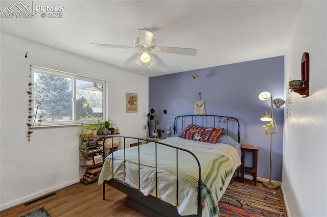 bedroom with ceiling fan, baseboards, visible vents, and wood finished floors