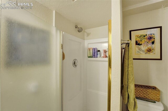 bathroom featuring a textured ceiling, toilet, and a shower stall