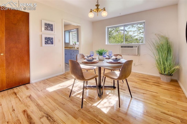 1227 Holmes Dr, Colorado Springs, CO 80909 - dining room featuring a chandelier, a wall mounted AC, light wood-type flooring, and baseboards