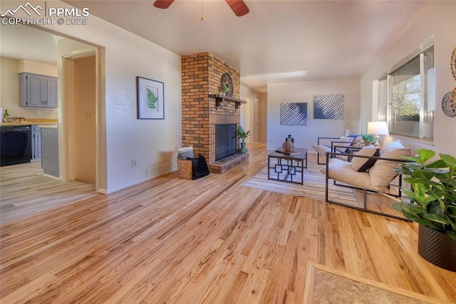 1227 Holmes Dr, Colorado Springs, CO 80909 - living room with a ceiling fan, light wood-style floors, a brick fireplace, and baseboards