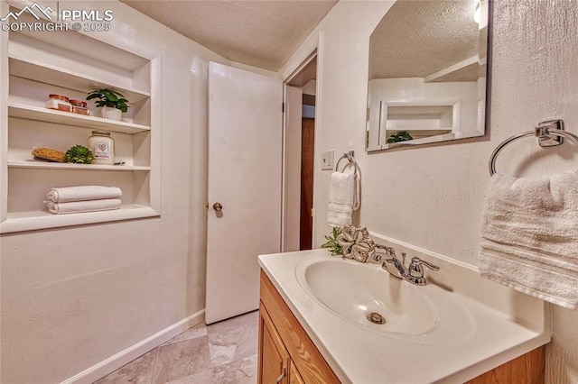 1227 Holmes Dr, Colorado Springs, CO 80909 - bathroom featuring a textured ceiling, vanity, baseboards, and built in features