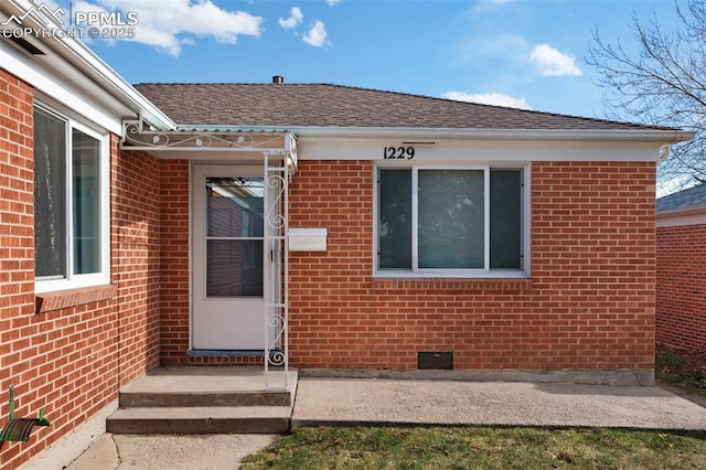 1229 E Caramillo St, Colorado Springs, CO 80909 - view of exterior entry with brick siding, crawl space, and roof with shingles