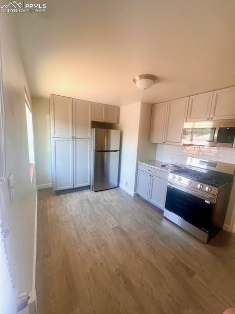 1229 E Caramillo St, Colorado Springs, CO 80909 - kitchen featuring appliances with stainless steel finishes, decorative backsplash, light wood-style floors, and baseboards