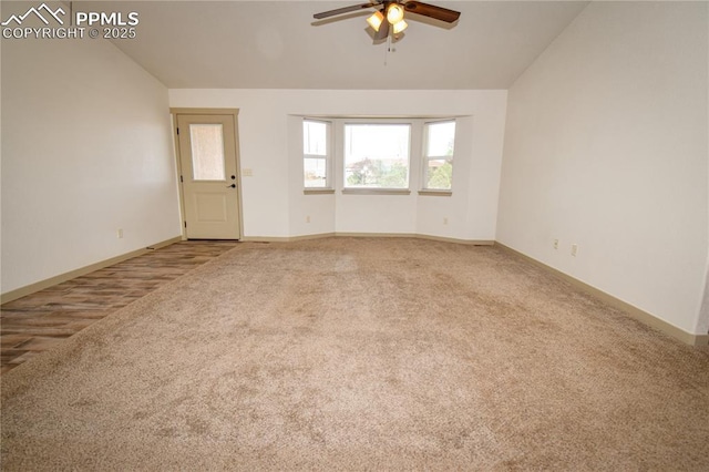 carpeted spare room featuring ceiling fan, baseboards, and lofted ceiling