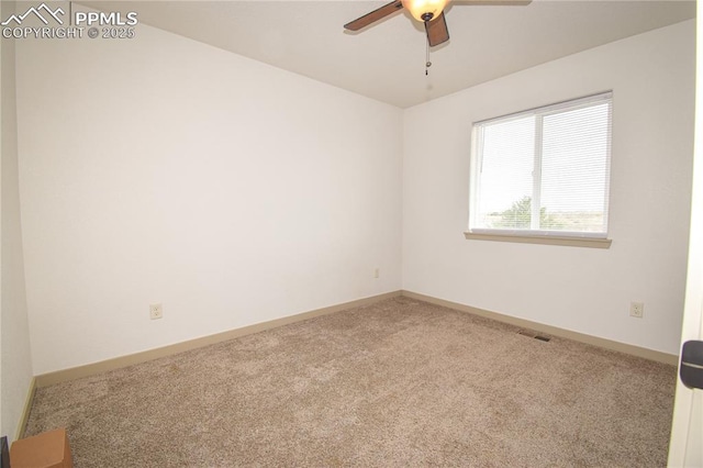 carpeted empty room with baseboards, a ceiling fan, and visible vents