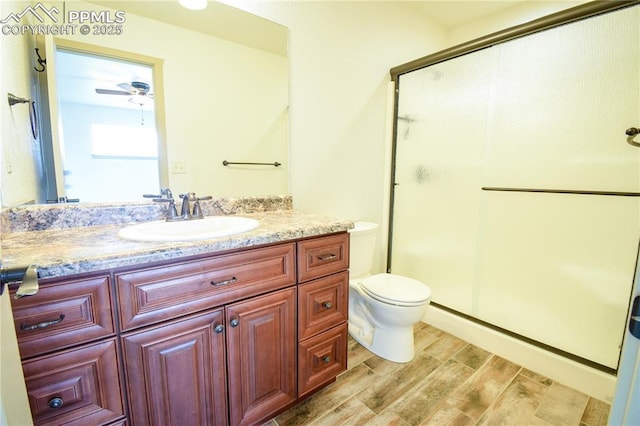 full bath with vanity, a stall shower, toilet, and wood finished floors