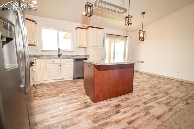 kitchen featuring a sink, light wood-style flooring, appliances with stainless steel finishes, and a kitchen island