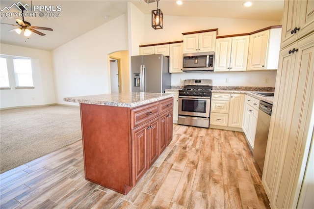 kitchen featuring ceiling fan, arched walkways, stainless steel appliances, open floor plan, and light wood-type flooring