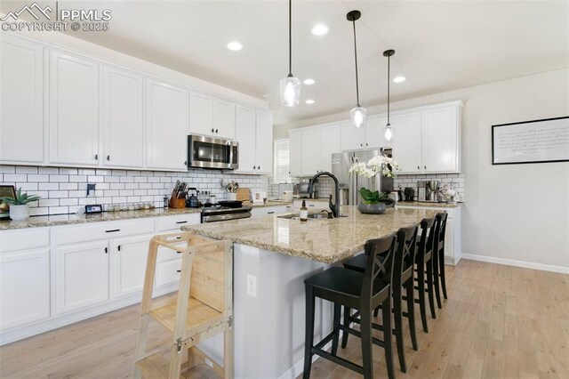 3111 Youngheart Way, Castle Rock, CO 80109 - kitchen with appliances with stainless steel finishes, a sink, backsplash, white cabinets, and a breakfast bar area