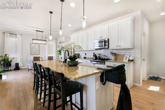 3111 Youngheart Way, Castle Rock, CO 80109 - kitchen with stainless steel microwave, stove, decorative backsplash, light wood finished floors, and recessed lighting