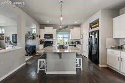 kitchen featuring plenty of natural light, black appliances, white cabinetry, and dark wood-type flooring