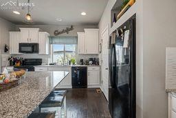 kitchen with dark wood finished floors, recessed lighting, white cabinetry, and black appliances