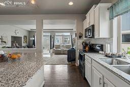 kitchen with black microwave, electric range oven, white cabinetry, recessed lighting, and dark wood-type flooring
