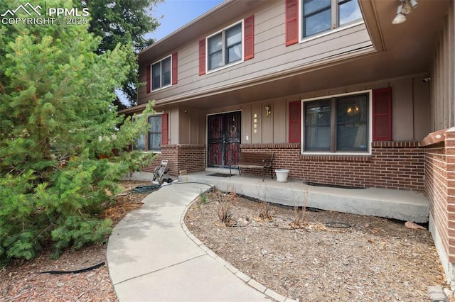6820 Dauntless Ct, Colorado Springs, CO 80919 - view of exterior entry featuring board and batten siding, brick siding, and a porch