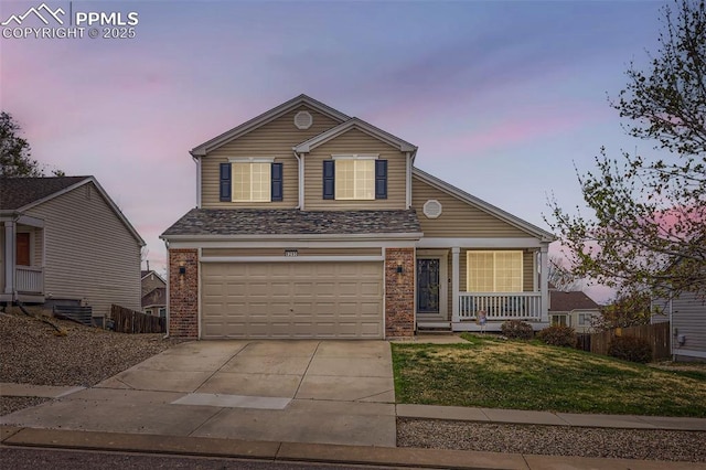 traditional home featuring brick siding, a garage, a porch, a yard, and driveway