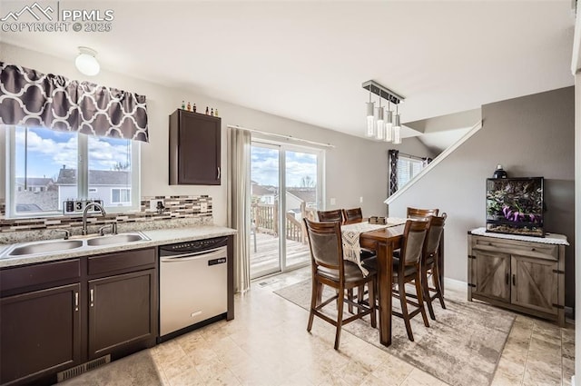 kitchen with dark brown cabinetry, a sink, dishwasher, light countertops, and backsplash