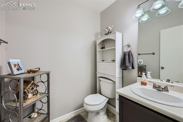 bathroom featuring baseboards, vanity, and toilet