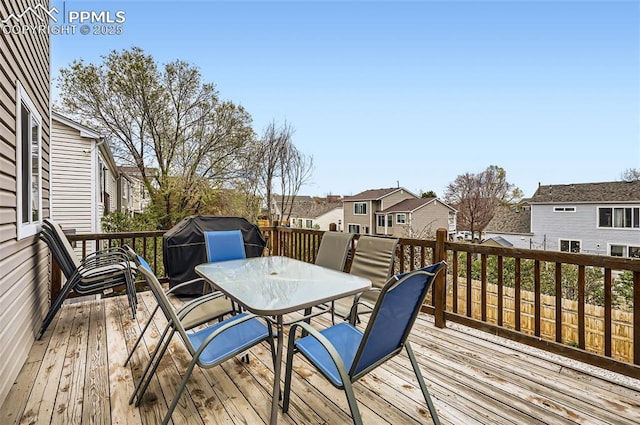 wooden deck featuring outdoor dining area, grilling area, and a residential view