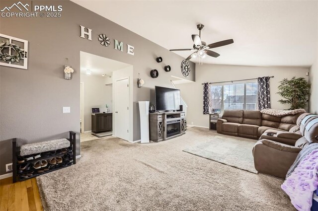living area with baseboards, a ceiling fan, carpet, and vaulted ceiling