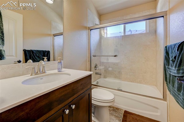 full bathroom featuring vanity, a textured wall, combined bath / shower with glass door, and toilet