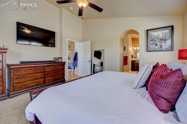 bedroom featuring arched walkways, ceiling fan, lofted ceiling, and ensuite bath