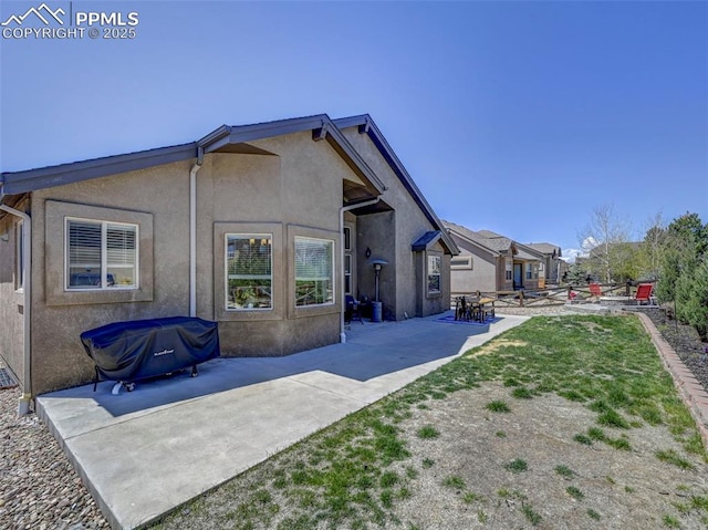 rear view of house with stucco siding and a patio area