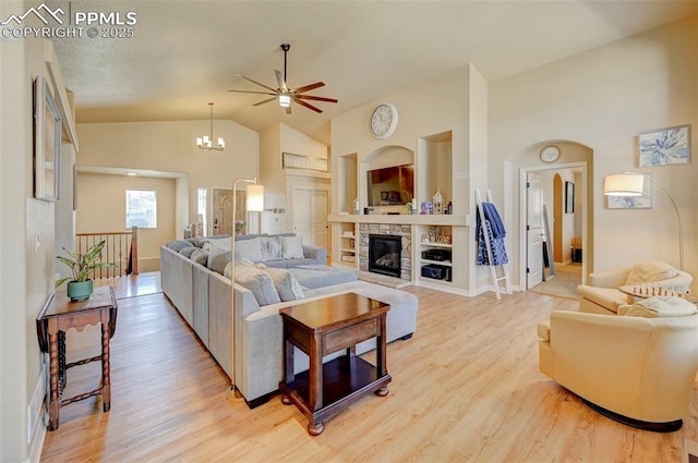 living area with a ceiling fan, a fireplace, high vaulted ceiling, baseboards, and light wood finished floors