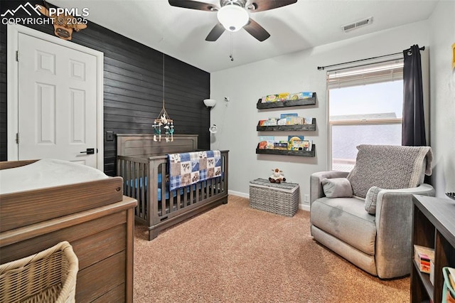 bedroom with a nursery area, light carpet, a ceiling fan, baseboards, and visible vents