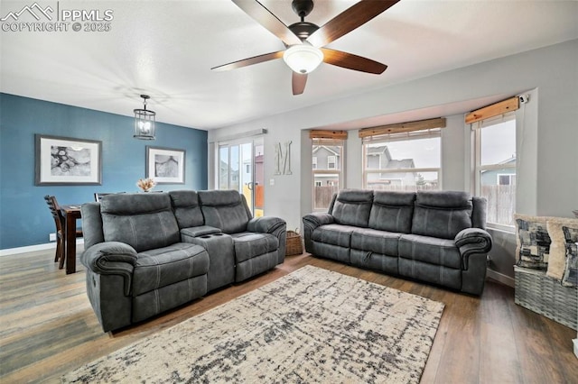 living room featuring a ceiling fan, baseboards, and wood finished floors