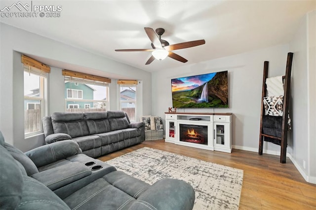 living area featuring a ceiling fan, baseboards, and wood finished floors