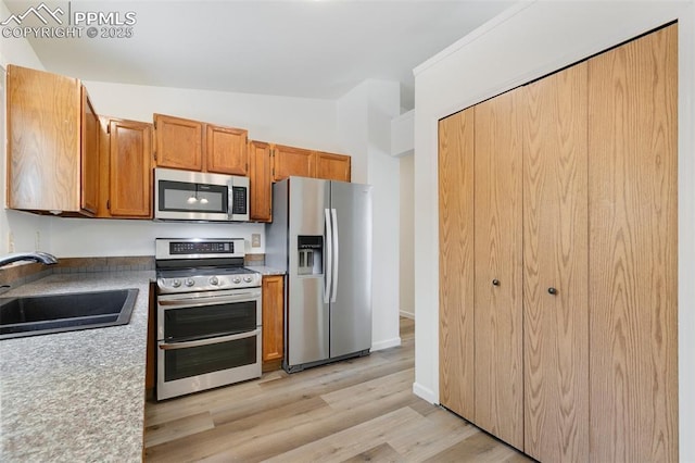 2706 N Chestnut St, Colorado Springs, CO 80907 - kitchen with appliances with stainless steel finishes, a sink, light wood-type flooring, brown cabinets, and light countertops