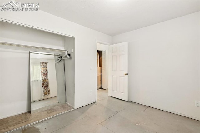 unfurnished bedroom featuring baseboards, concrete floors, and a closet