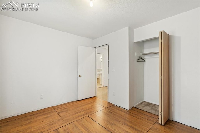 unfurnished bedroom with wood finished floors and a closet