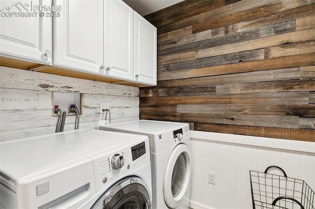 washroom with cabinet space, washer and dryer, and wooden walls