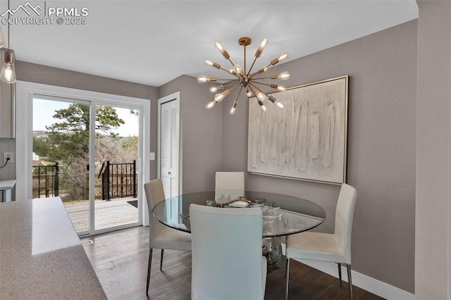 dining area with baseboards, a notable chandelier, and wood finished floors