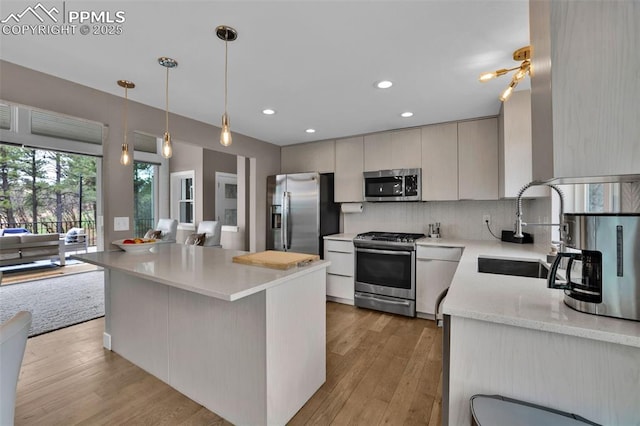 kitchen with recessed lighting, tasteful backsplash, a sink, light wood finished floors, and appliances with stainless steel finishes