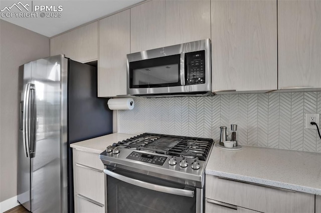 kitchen with appliances with stainless steel finishes, tasteful backsplash, modern cabinets, and light stone counters