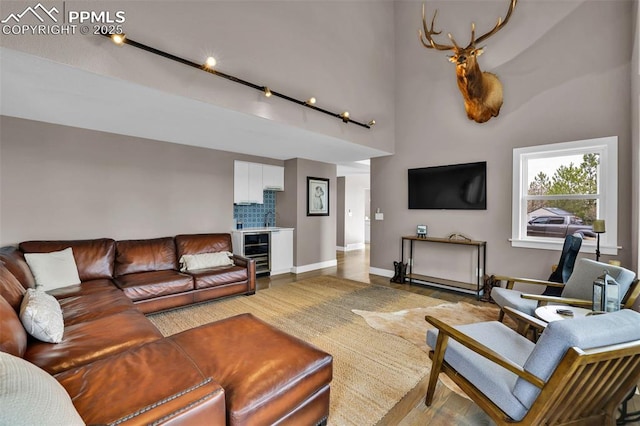 living area featuring baseboards, a high ceiling, and beverage cooler